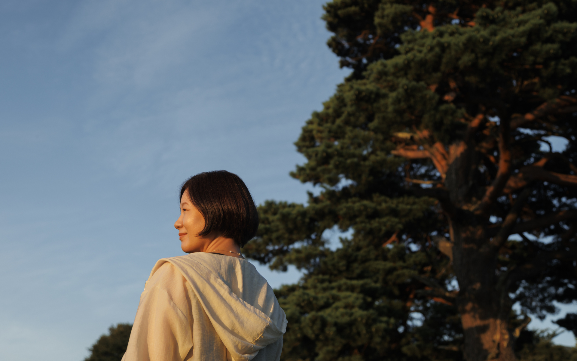 Image of woman walking in the forest under a clear blue sky